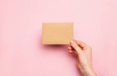 El işi, pembe arka planda boş kağıt kartıyla. Boşluğu kopyala, metin için boşluk. Tasarım için model şablonu.