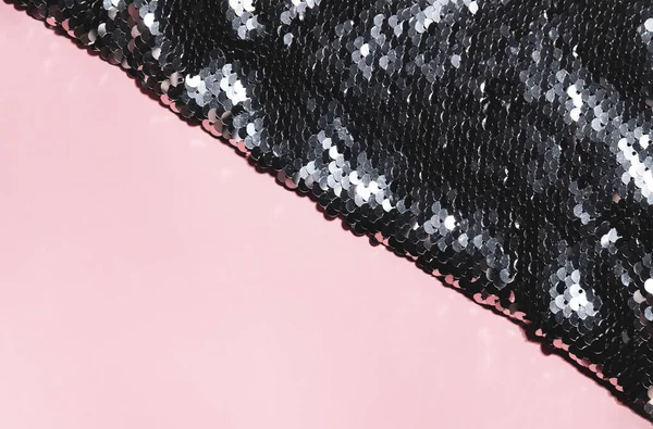 Texture of precious black and silver sequins shining round sequins on pink background. Fashion glamour concept. Scales of sparkling sequins.