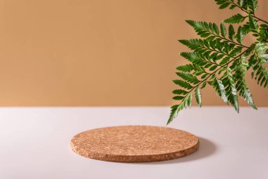 Yeşil yapraklı eğreltiotu ile yuvarlak geometrik şekilli ahşap kürsü. Ürün ve malları sergilemek için boş bir vitrin. Kozmetik ve eko ürün sunumu için minimalist bileşim doğal bej
