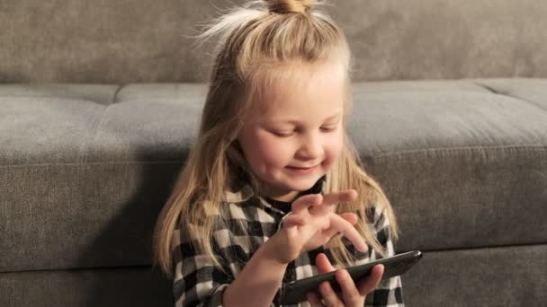 小さな女の子の子供は スマートフォンを使用して モバイルゲームアプリをプレイ 子供のための教育ゲームとアプリケーション — ストック動画