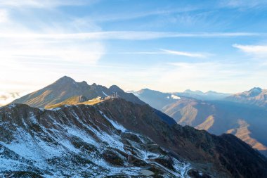 Karlı yüksek dağın tepesinde ve güneşli bir günde bulutlar