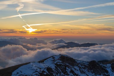 Karlı yüksek dağlar mavi gökyüzündeki bulutlar arasında