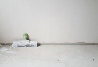 Beton zemindeki duvarın yanındaki boş odada macun bıçağı. Oda içi arka plan.