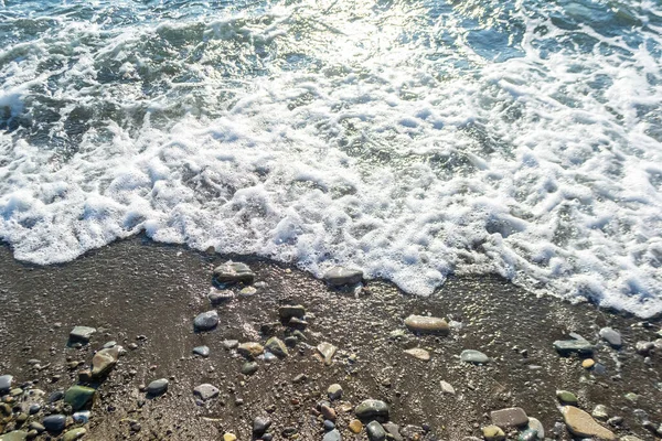 阳光普照的海滩上湿透的沙子 卵石和泡沫 夏季背景 — 图库照片