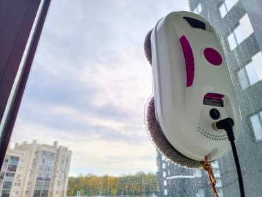 Elektrikli süpürge robotu cam pencereyi yıkıyor. Robot pencere temizleyicisi evde pencereleri temizliyor.