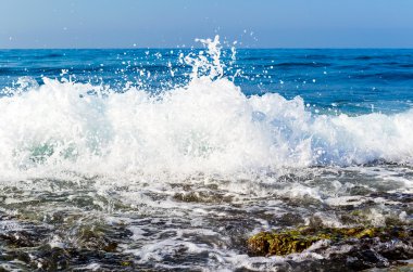 The waves breaking on a stony beach, forming sprays