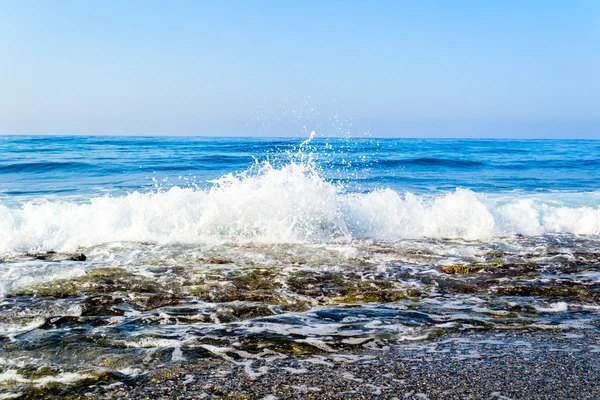 Vagues se brisant sur une plage pierreuse, formant des sprays — Photo