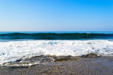 Taşlı bir kumsalda kırma dalgalar spreyler şekillendirme