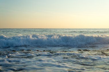 Taşlı bir kumsalda kırma dalgalar spreyler şekillendirme