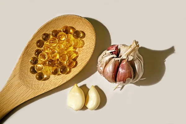 Pearls of garlic oil on wooden spoon — Stock Photo, Image