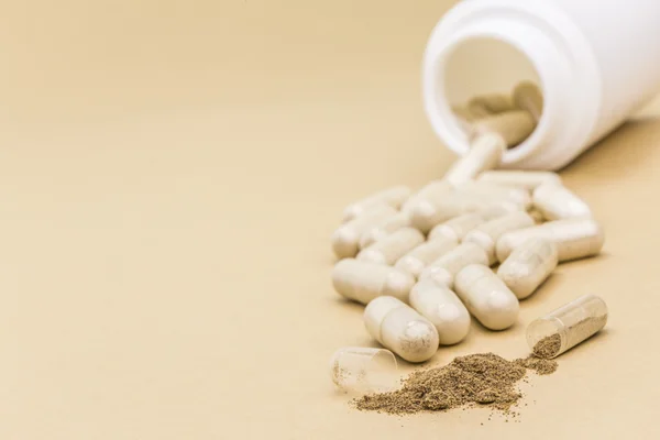 Pills spilling from an open bottle on brown background — Stock Photo, Image