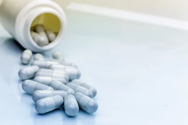 Pills spilling from an open bottle on brown background — Stock Photo, Image