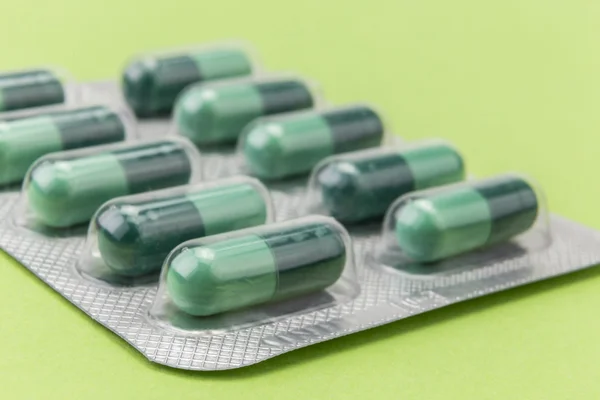 Pills capsules medicine on green background — Stock Photo, Image