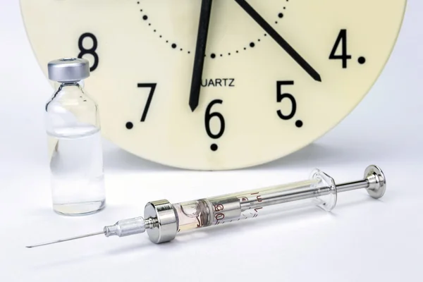 Frascos de medicamentos y jeringa, el reloj muestra la hora de la medi — Foto de Stock