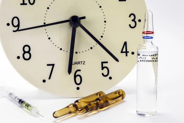 Frascos de medicamentos y jeringa, el reloj muestra la hora de la medi — Foto de Stock