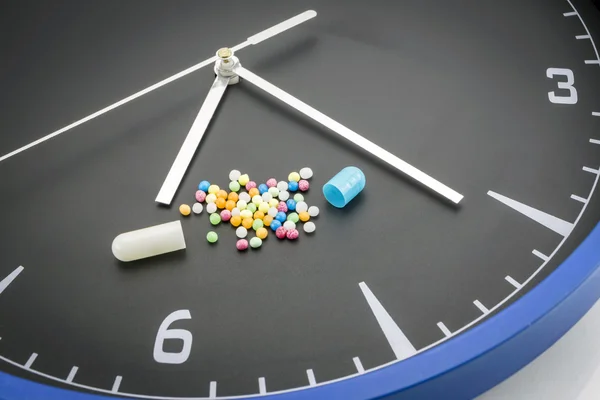 Pilule capsule rouge ouverte avec médicament de couleur balle sur backgr horloge noire — Photo