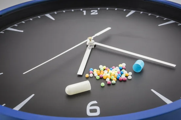 Open red capsule pill with ball color drug on black clock backgr — Stock Photo, Image