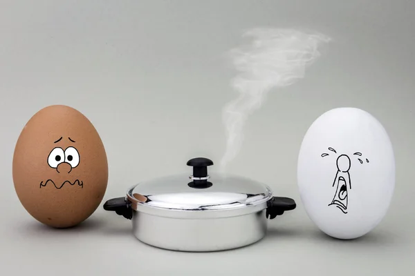 Two eggs look with strange face to a hot pot to be cooked — Stock Photo, Image