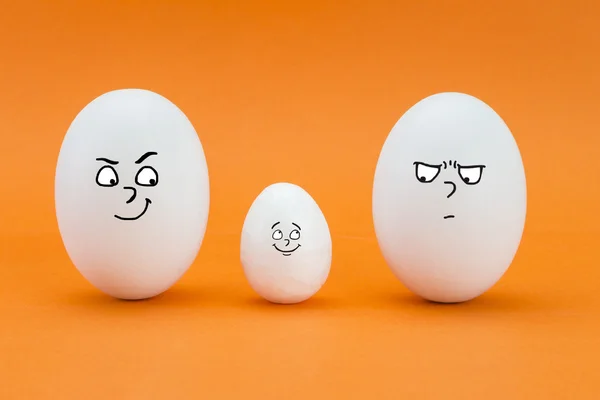 Two big eggs look with face of few friends at a small egg — Stock Photo, Image