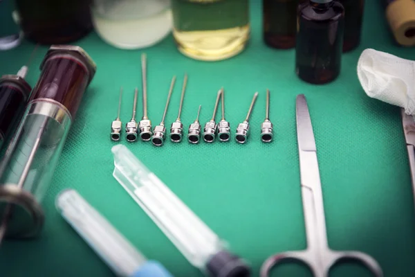 Op のテーブルで注射器の横にさまざまなサイズの針の金属 — ストック写真