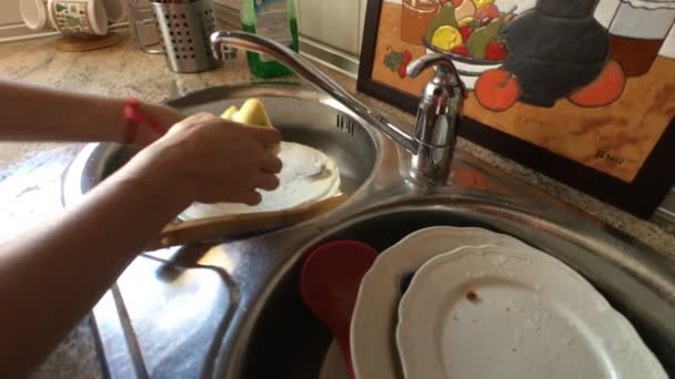 Mujer de mediana edad lava los platos en el fregadero de la cocina — Vídeo de stock