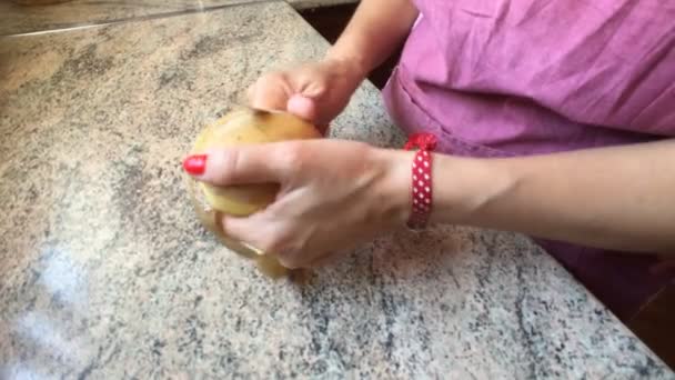 Vrouw van middelbare leeftijd in de keuken peeling een aardappel — Stockvideo