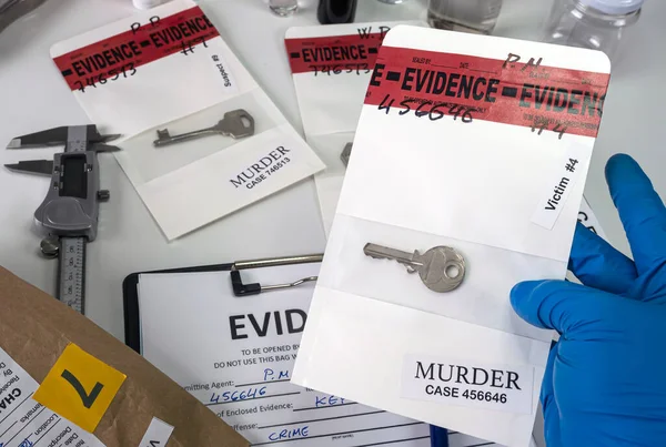 警察科学家拿着装有实验室谋杀案受害者钥匙的样品袋 概念图像 — 图库照片