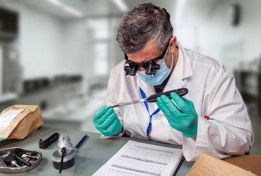 Adli polis, suç laboratuarında kullanılan bıçağı büyüteç ve konsept görüntüyle analiz etti.