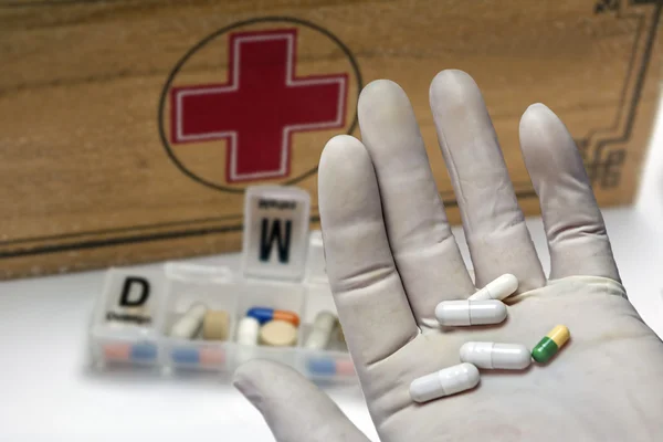 Pills with pill organizer next to old wood kit — Stock Photo, Image