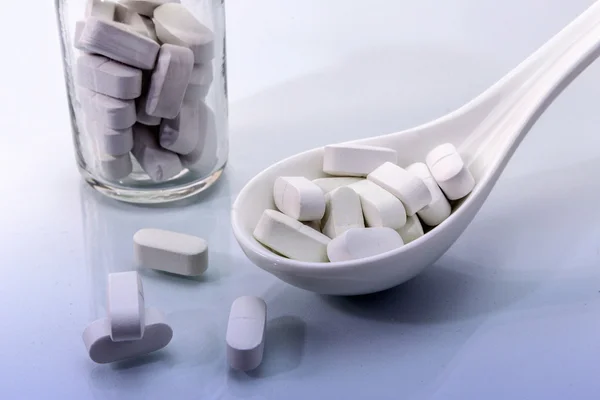 Cuillère blanche avec quelques pilules, concept de santé — Photo