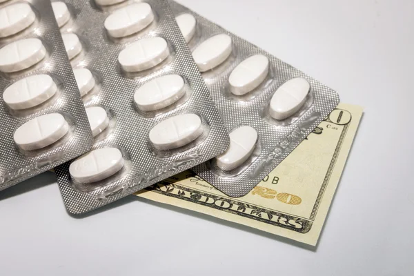 Blister van witte pillen op de top van biljetten van 20 dollar, concept van gezondheid copay — Stockfoto