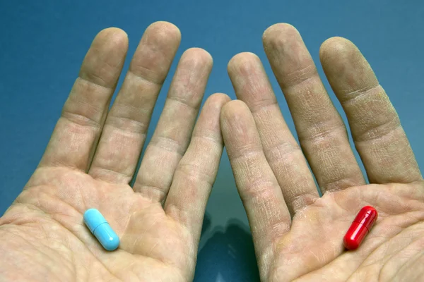 Mãos com cápsula vermelha e azul — Fotografia de Stock