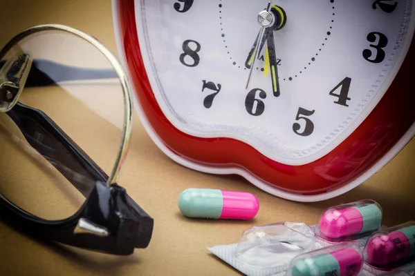 Några piller och röd klocka, daglig medicinering behandling — Stockfoto