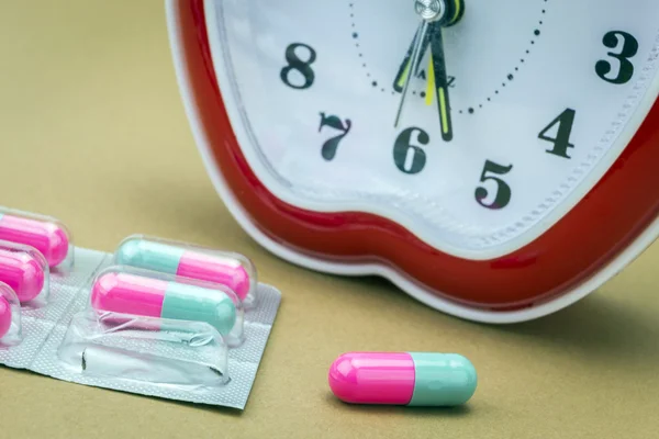Some pills and red clock, daily medication treatment — Stock Photo, Image