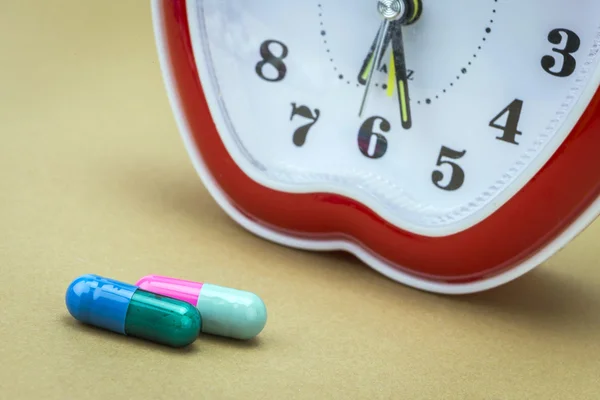 Some pills and red clock, daily medication treatment — Stock Photo, Image