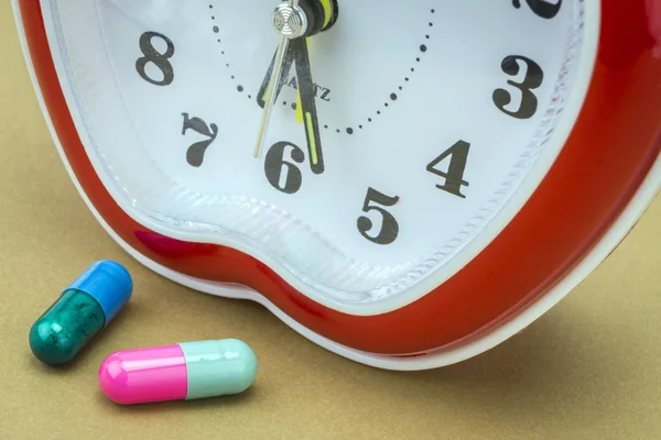 Some pills and red clock, daily medication treatment — Stock Photo, Image