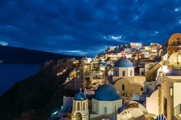 Iglesias de Oia pueblo al atardecer con cielo dramático, Santorini — Foto de Stock