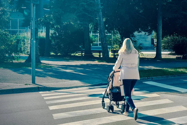 엄마는 보행자 도로를 건너고 아기를 데리고 유모차를 건너고 있어요 — 스톡 사진