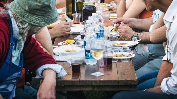 İnsanlar bir kasaba festivalinde yemek yiyor, tipik bir açık hava yemeğinin yatay görüntüsü (İtalyan kültürünün neşeli anı))