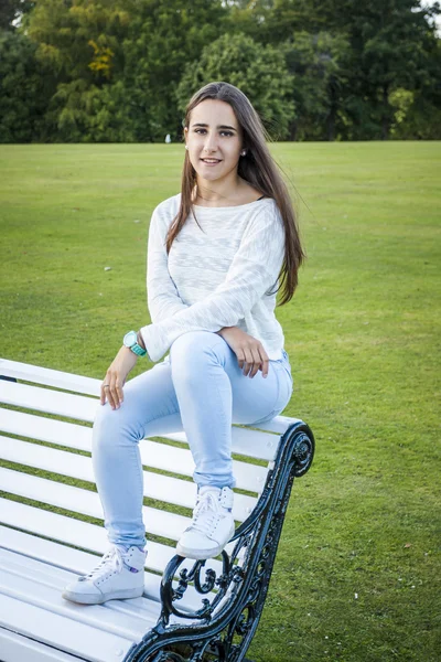 Jeune fille assise sur un banc de parc — Photographie 