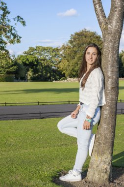 Güzel genç bir ağaca yaslanmış