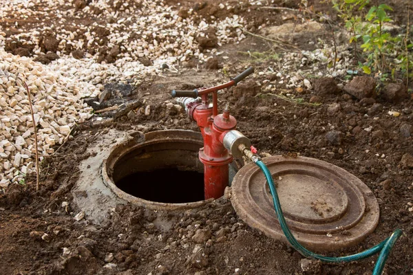 Cleaning manhole, sewer, repair, maintenance in sewerage hatchway using a pump and hose in mud on construction site