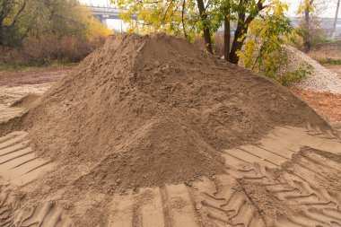 İnşaat için lastik izi olan kum yığını doğada çalışıyor.