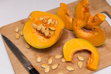 Tahta tahtada balkabağı sebzesi doğramak. Evde sağlıklı vejetaryen yemekleri pişirmek.