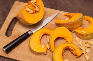 Tahta tahtada balkabağı sebzesi doğramak. Evde sağlıklı vejetaryen yemekleri pişirmek.