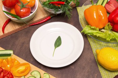 Farklı sebzeler ve beyaz tabakta ıspanak yeşili bir yaprak. Diyet, oruç, vegan, vejetaryen, sağlıklı gıda konsepti