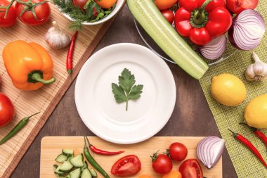 Pişirmek için farklı taze sebzeler ve beyaz tabakta bir maydanoz yeşili yaprak. Diyet, oruç, vegan, vejetaryen, sağlıklı gıda konsepti