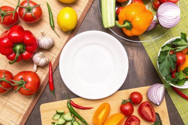 Pişirmek ve boş beyaz tabak için farklı sebzeler. Diyet, oruç, vejetaryen, sağlıklı, çiğ yiyecekler. 