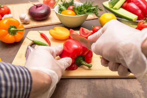 Chef cooking healthy vegetarian vegan diet food. Hands in latex gloves cutting red pepper paprika and vegetables