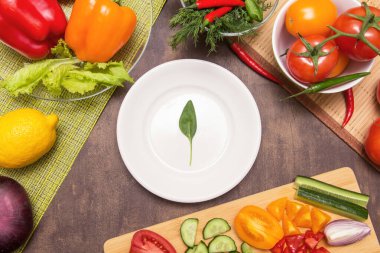 Yemek yapmak için farklı sebzeler ve boş beyaz tabakta ıspanak yeşili bir yaprak. Diyet, oruç, vegan, vejetaryen, sağlıklı gıda konsepti